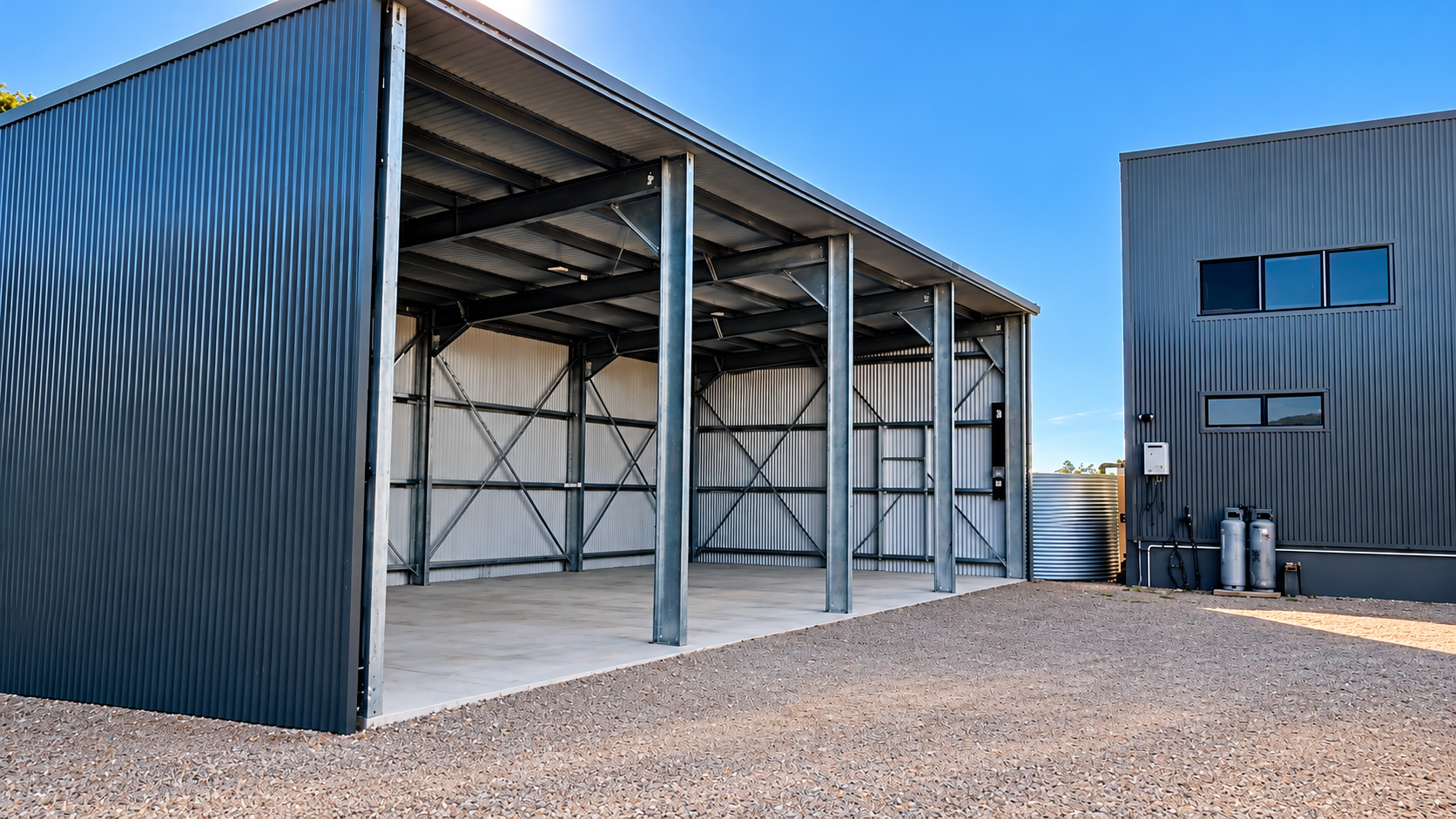 Open-front steel shed with dark corrugated cladding and a galvanised steel frame on a new concrete slab, built by Alcorn Constructions