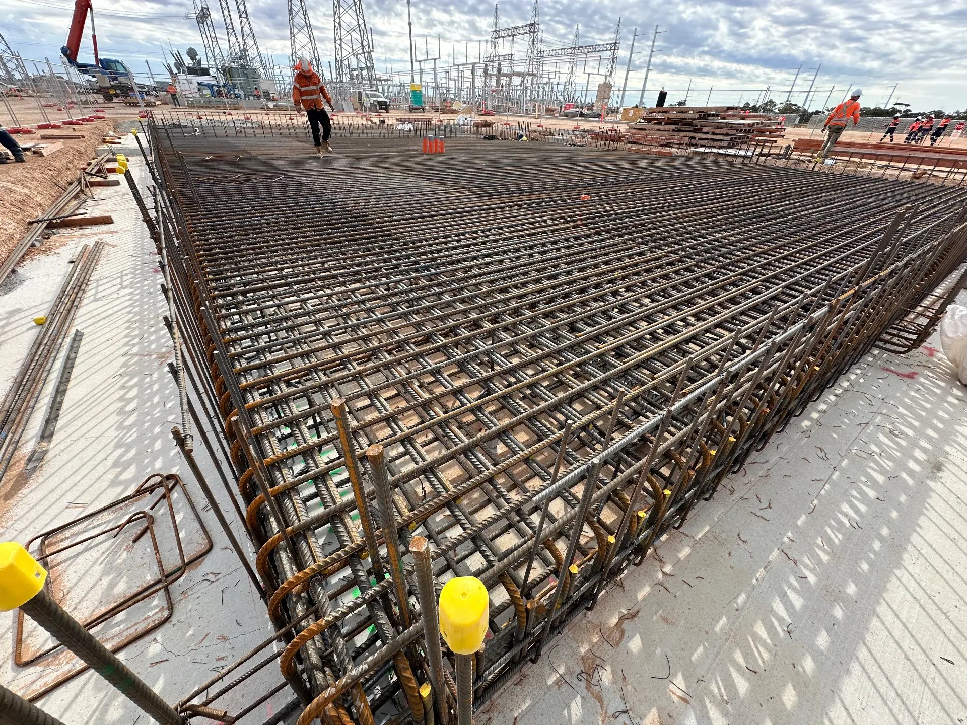 Steel reinforcement mat laid out across a large slab on a civil works site, ready for the pour